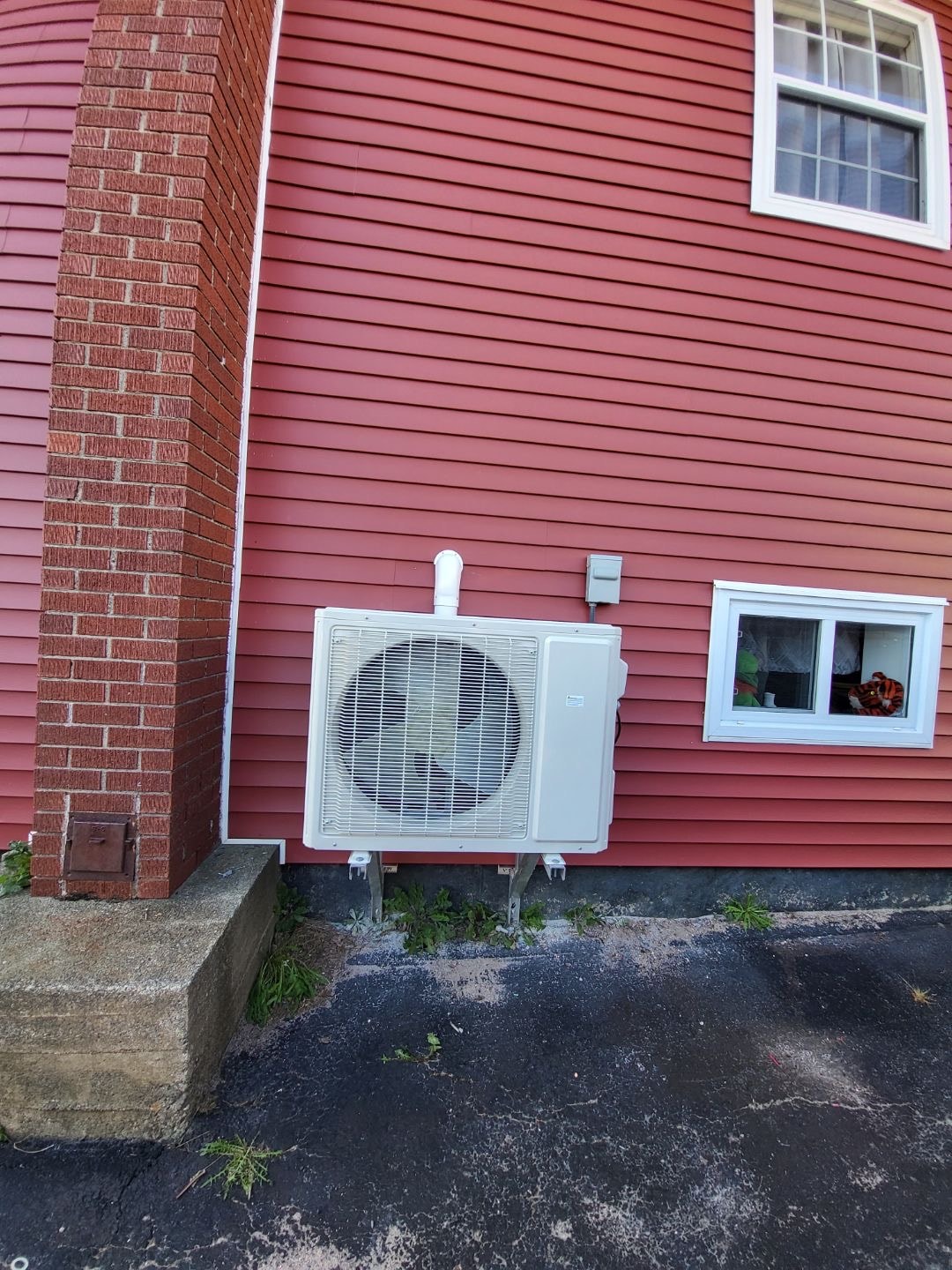 Heat pump outdoor unit on red brick and siding home