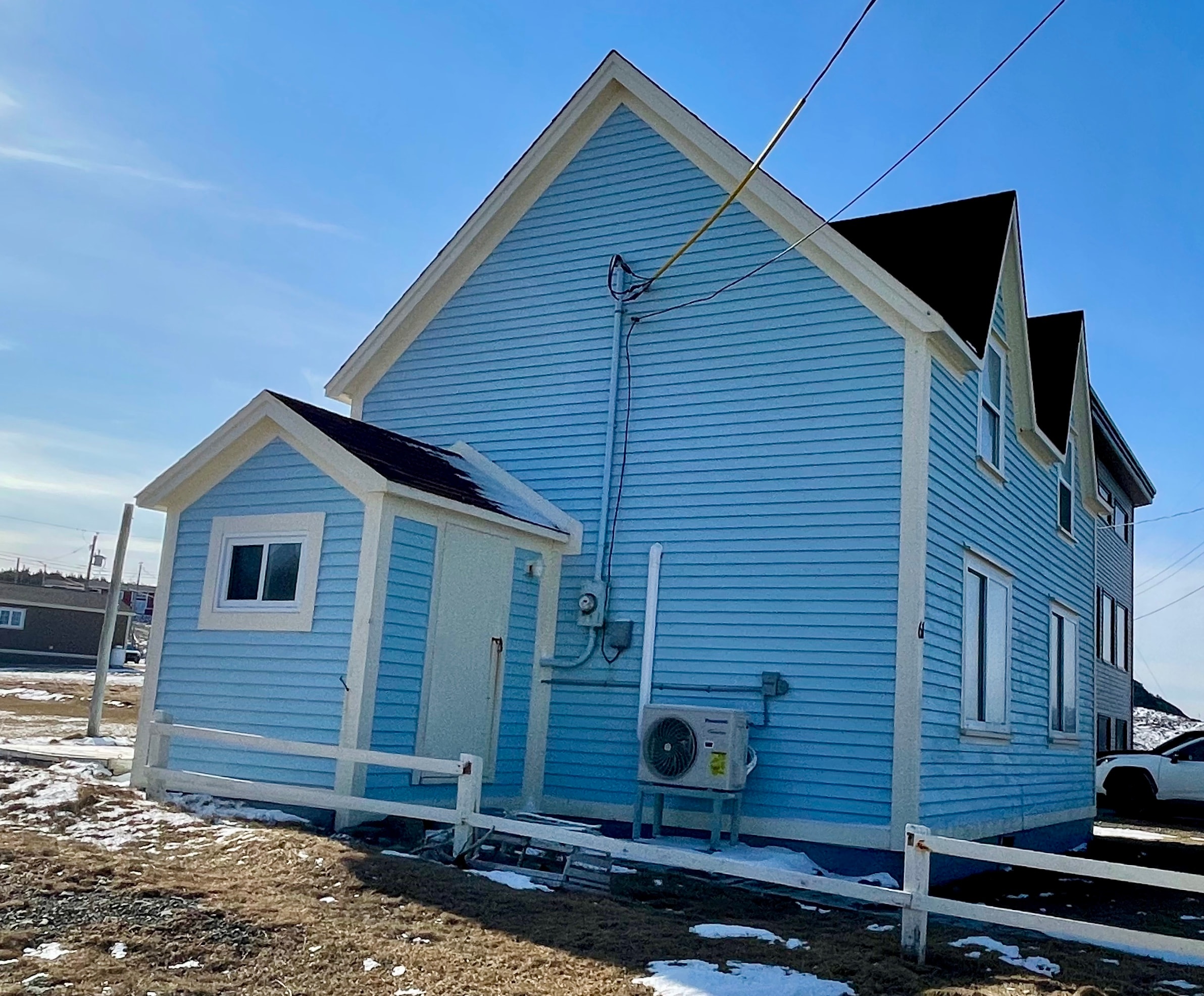 Panasonic heat pump on blue two-storey Newfoundland home