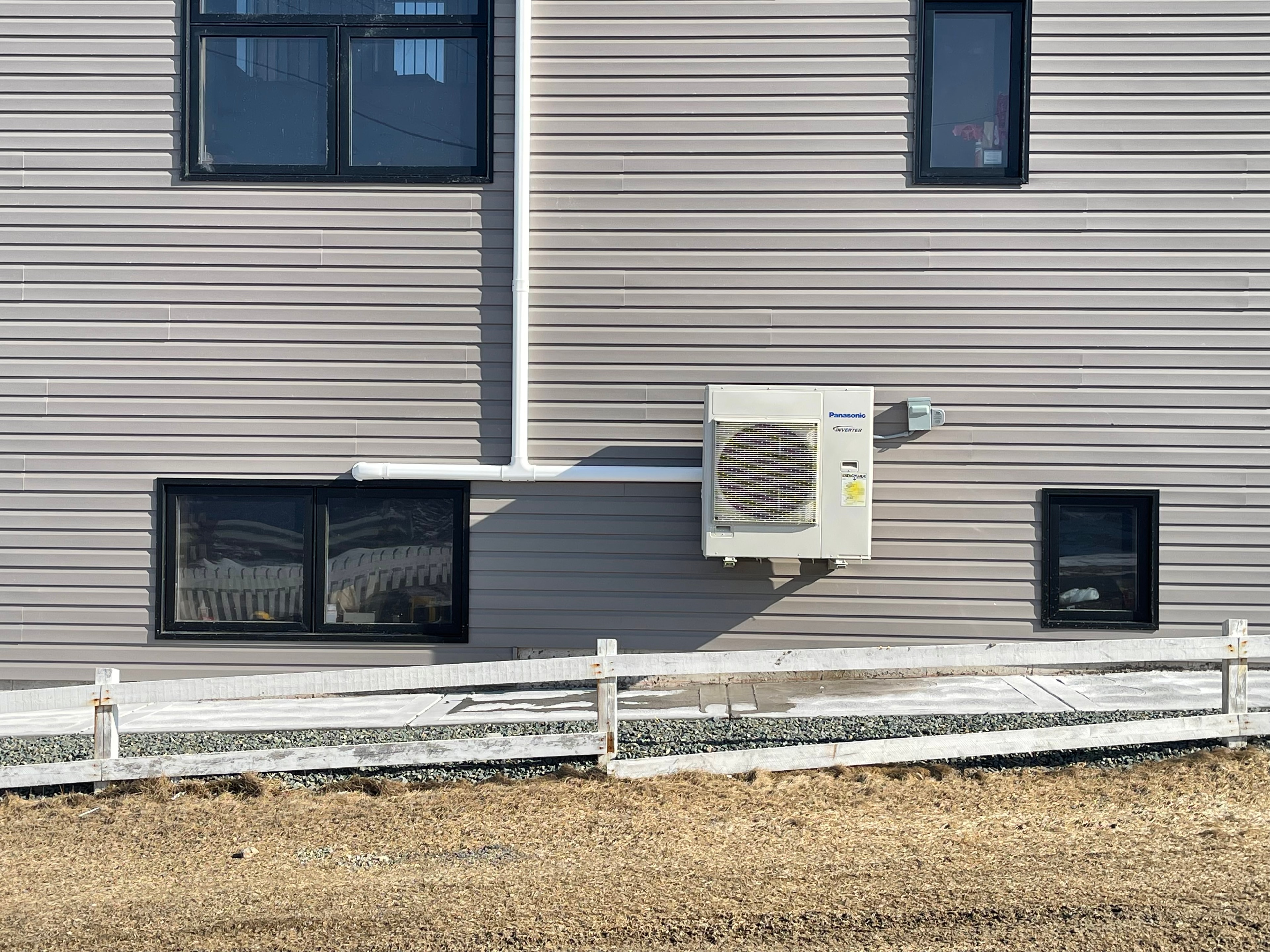 Panasonic heat pump mounted on grey siding new build